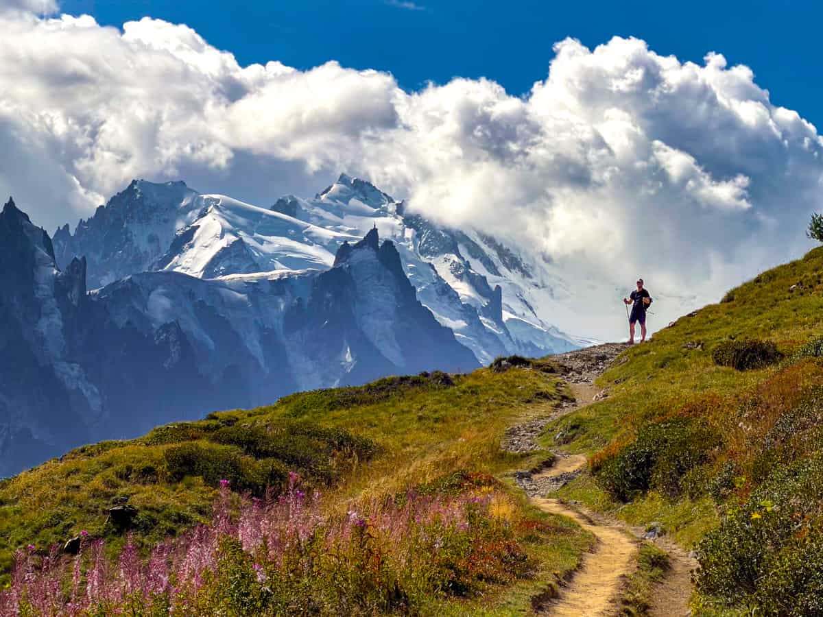 Man standing along the Tour du Mont Blanc with the Mont Blanc massif in the background near Chamonix, France