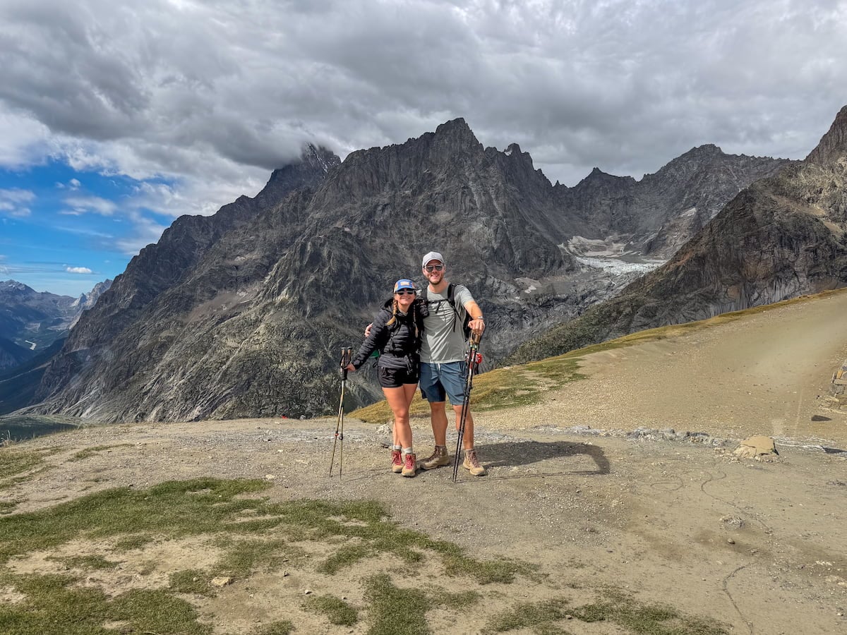 Smiling couple with the Italian Alps in the background at the Grand Col Ferret, Italy along the Tour du Mont Blanc