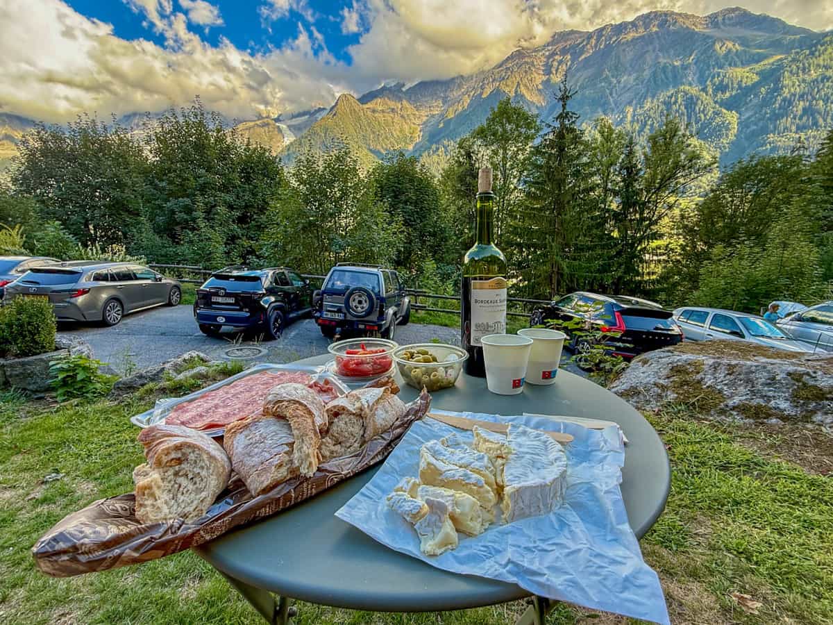 Cheese, baguettes, meats, olives, and wine with the French Alps in the background in Les Houches, France