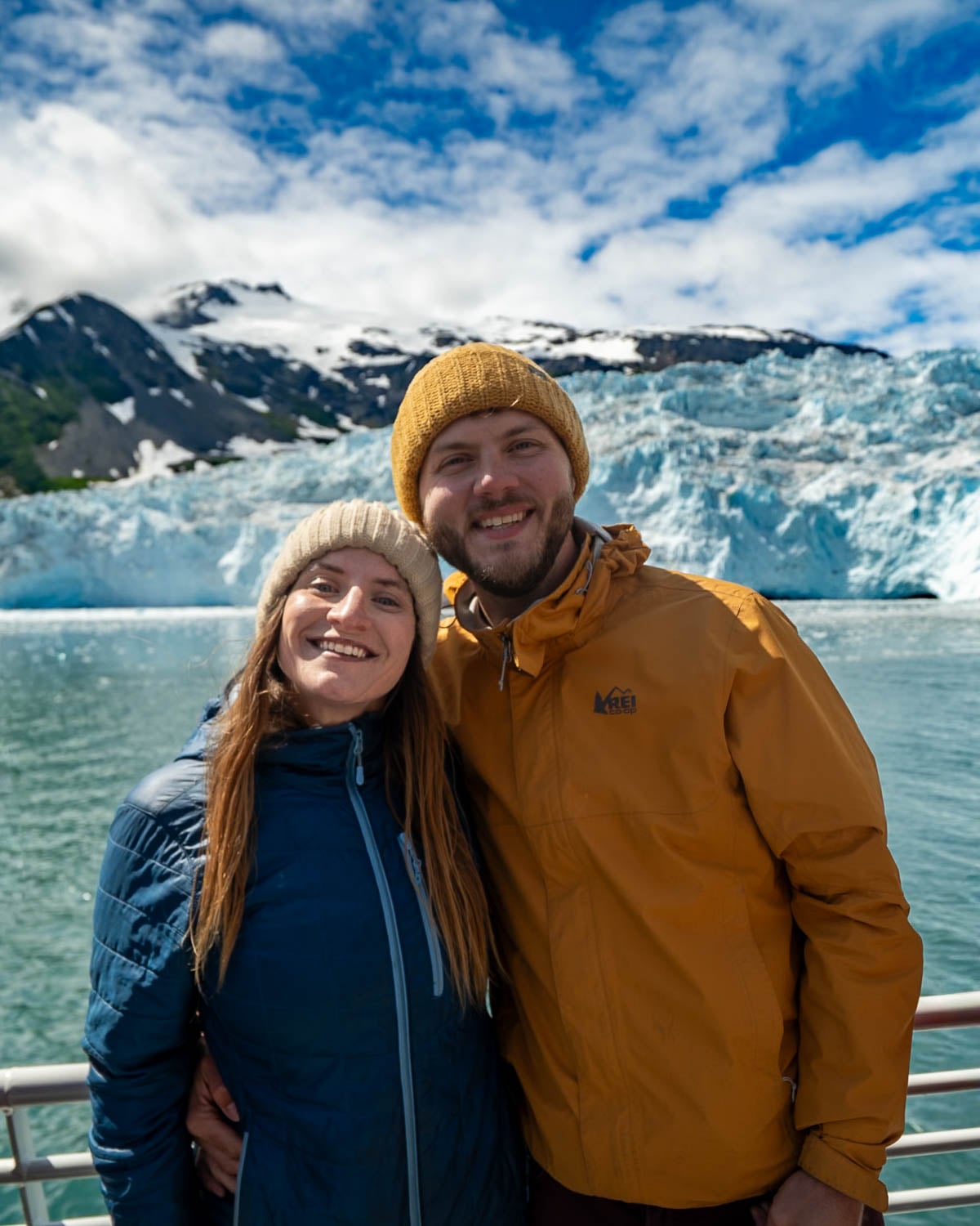 Couple smiling in front of a tidewater glacier on a Major Marine tour in Kenai Fjords National Park, Alaska