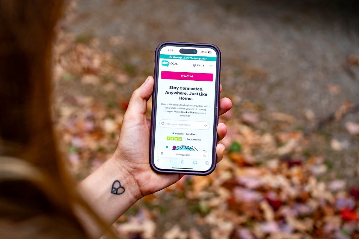 Woman holding a cell phone with Sim Local on the screen