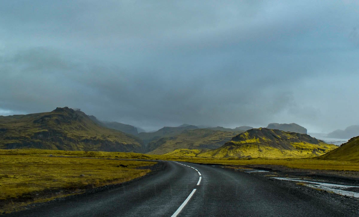 Road leading through green mossy volcanic mountains in Iceland