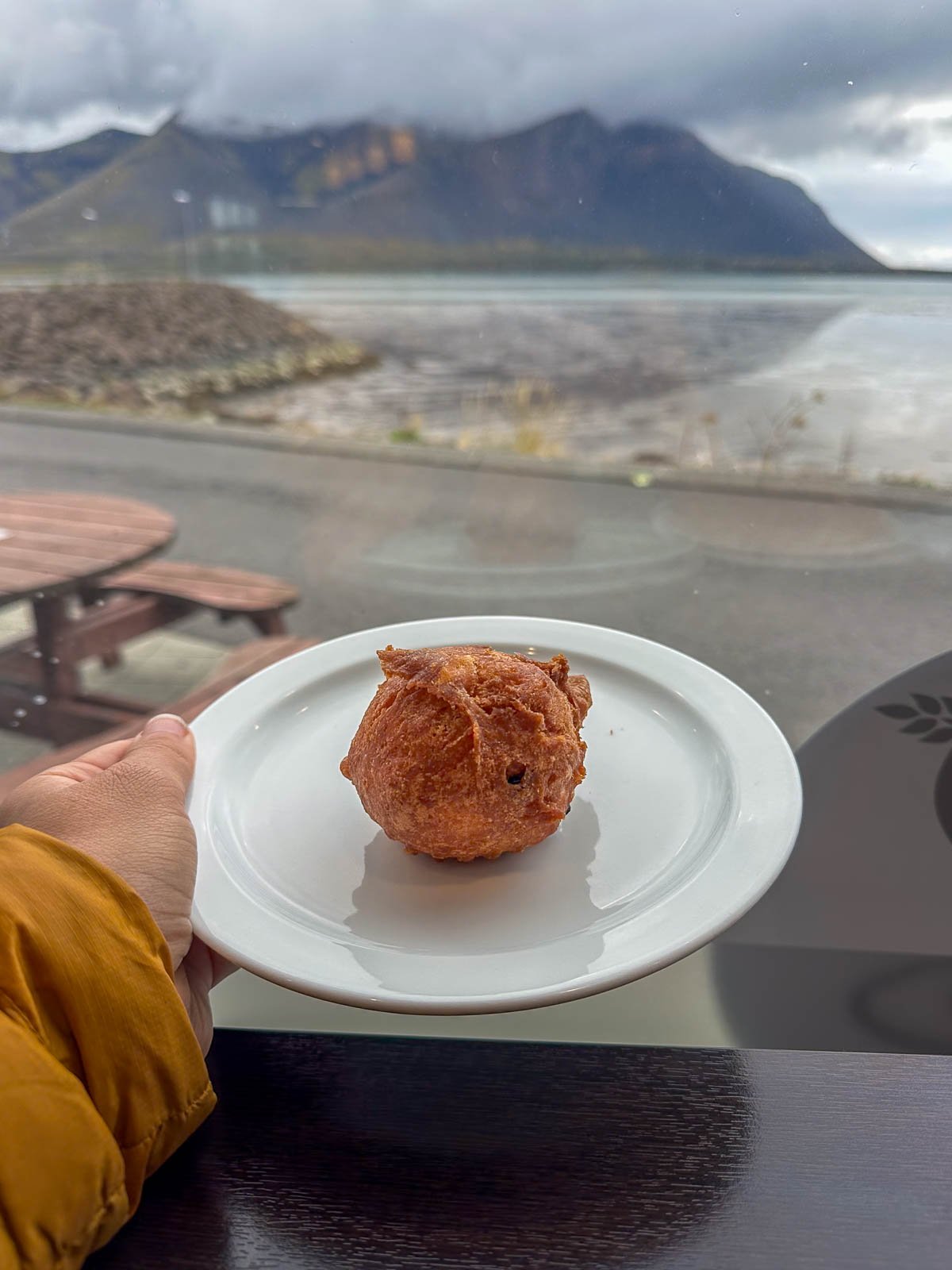 Woman holding a plate of ástarpungar in a bakery with a mountain in the background in Iceland