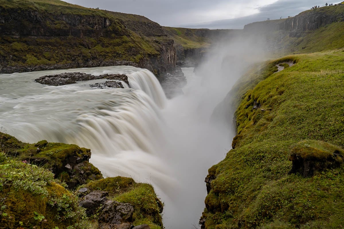 Misty waterfall at Gullfoss around green cliffs in Iceland