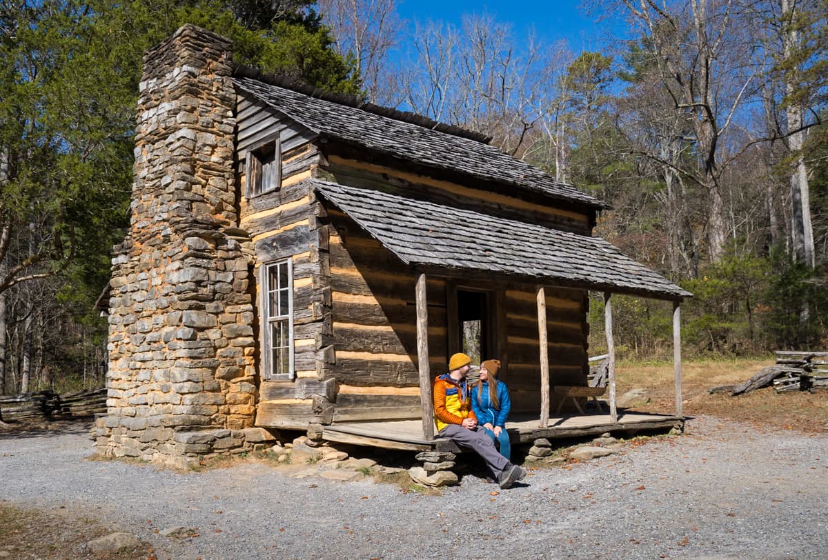 Couple sitting on the porch of a historic log cabin along the Cades Cove Loop in Great Smoky Mountains National Park