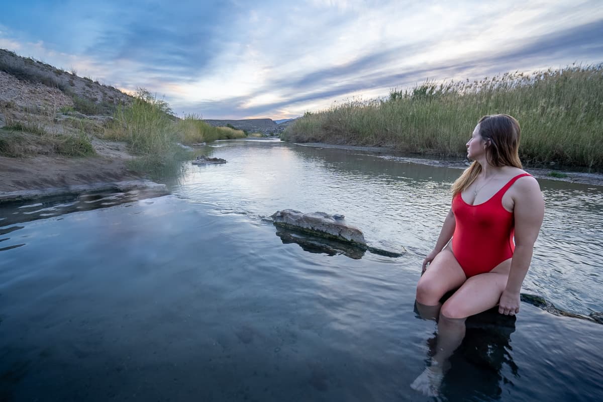 Woman sitting on the edge of the ruins of an old bathhouse in the Boquillas Hot Springs along the Rio Grande in Big Bend National Park