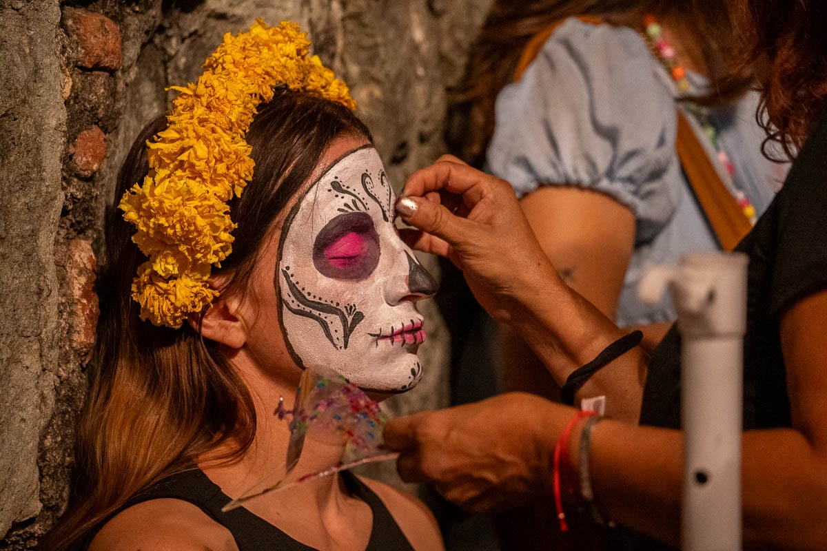Woman getting La Calavera Catrina makeup done during Day of the Dead in Oaxaca, Mexico