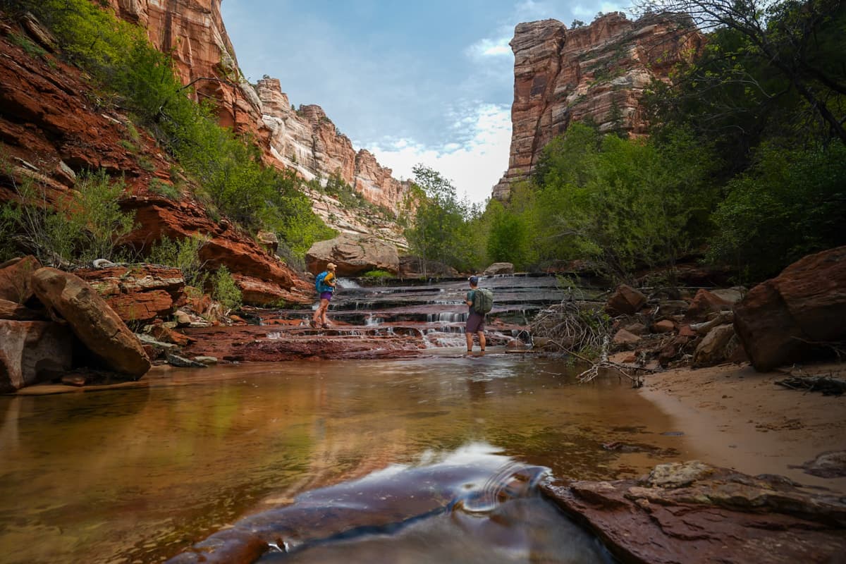 Couple standing on a waterfall along The Subway Trail in Zion National Park