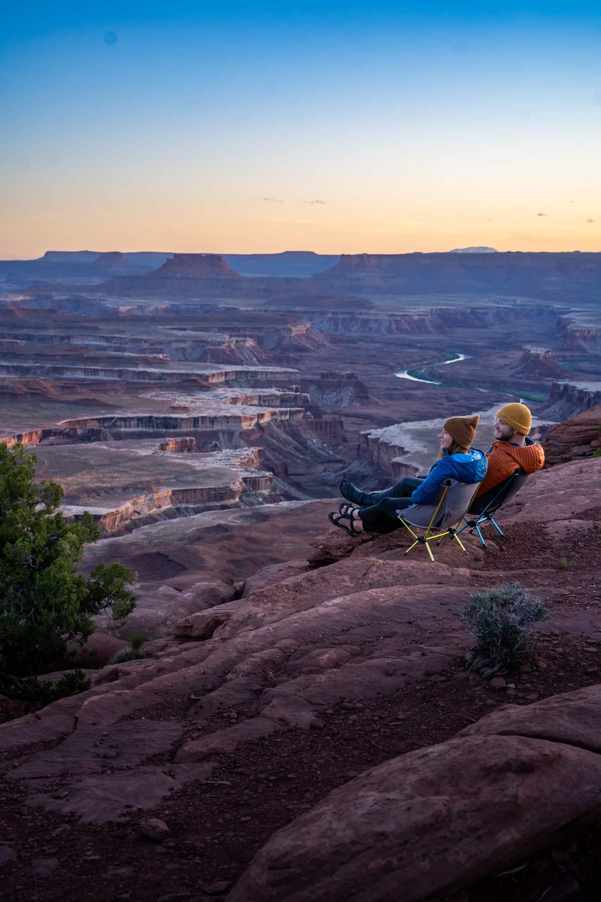 Couple sitting in camping chairs along the Green River Overlook in Canyonlands Natonal Park at sunset