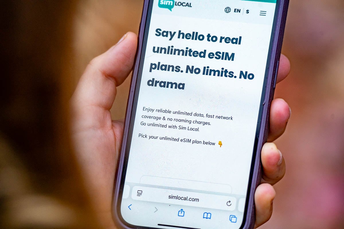 Woman holding a cell phone with unlimited data plans for an eSIM provider, Sim Local