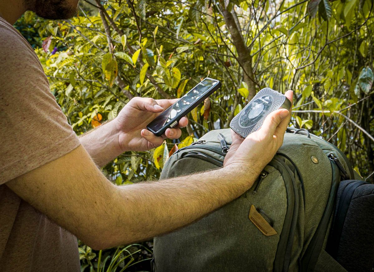 Man connecting a mobile router to his cell phone over a backpack in Costa Rica