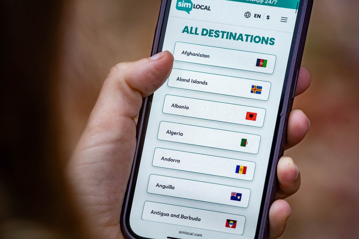 Woman looking at a cell phone with options for different destinations for Sim Local, an eSIM provider
