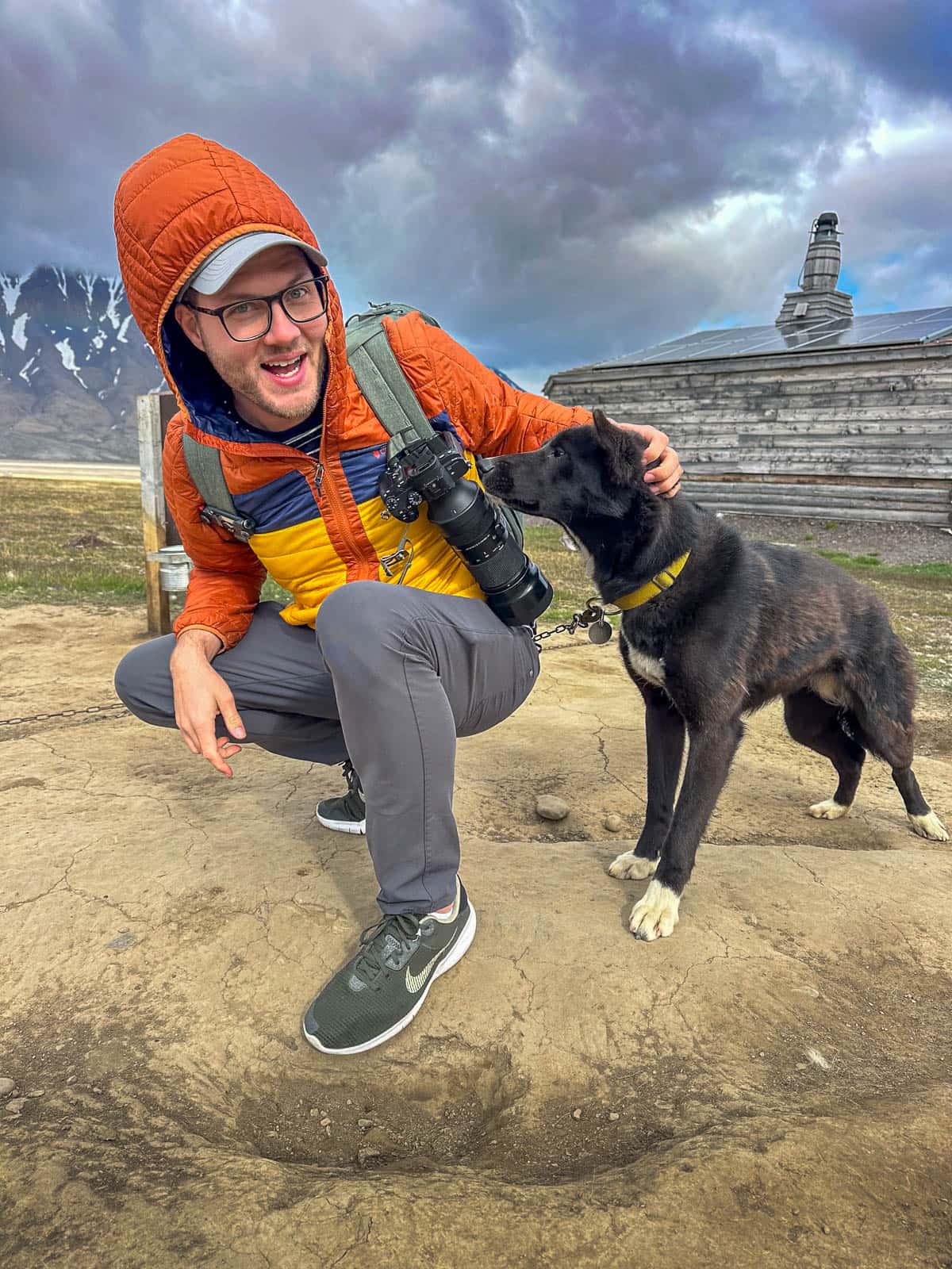 Smiling man pets sled dog in Longyearbyen in Svalbard, Norway