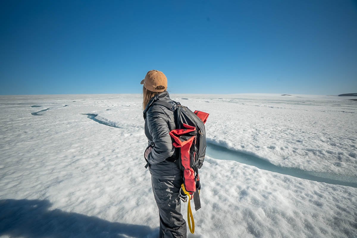 Woman standing on a glacier with a glacial stream in the background in Svalbard, Norway