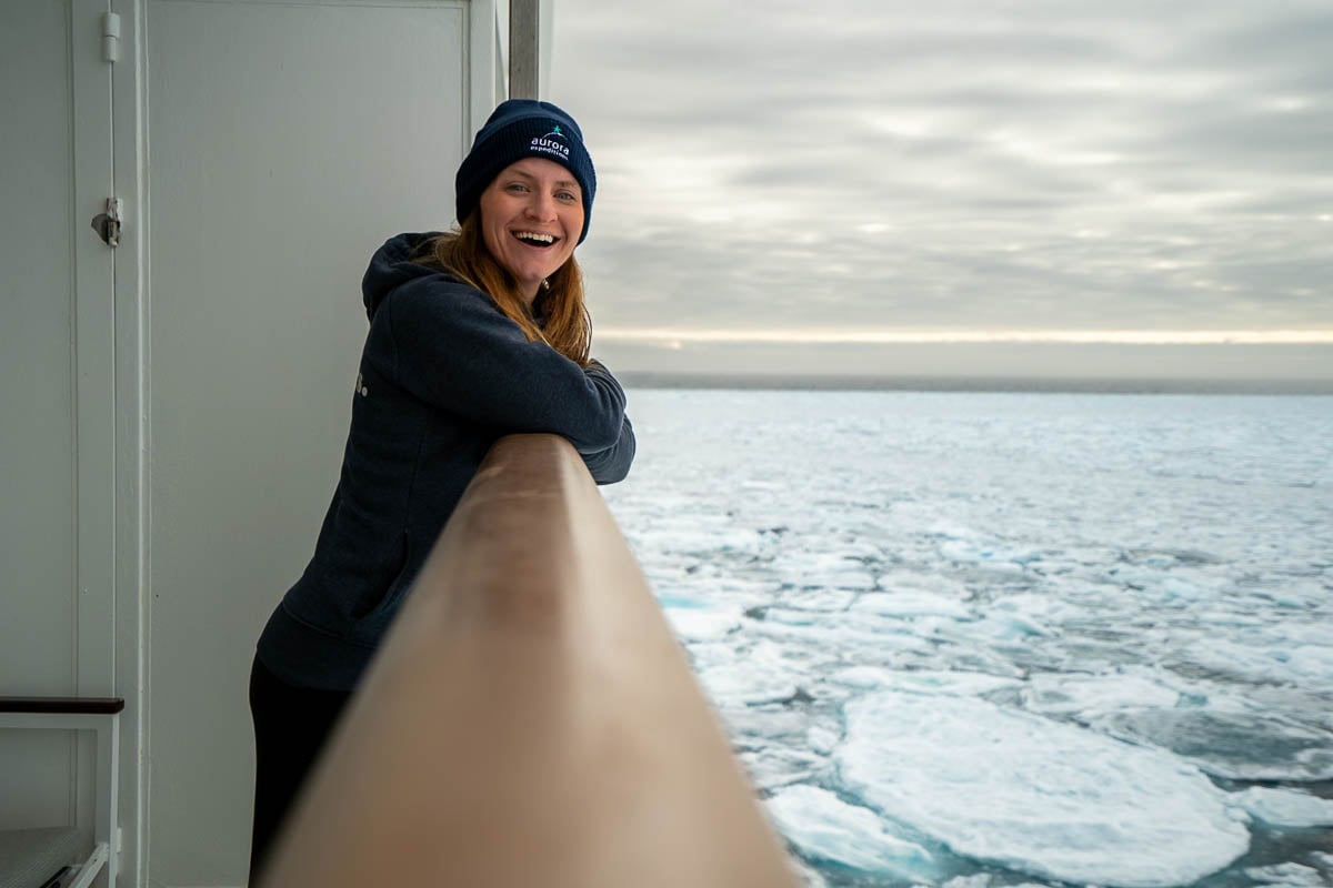 Woman smiling on a balcony with pack ice in the background on a Svalbard cruise