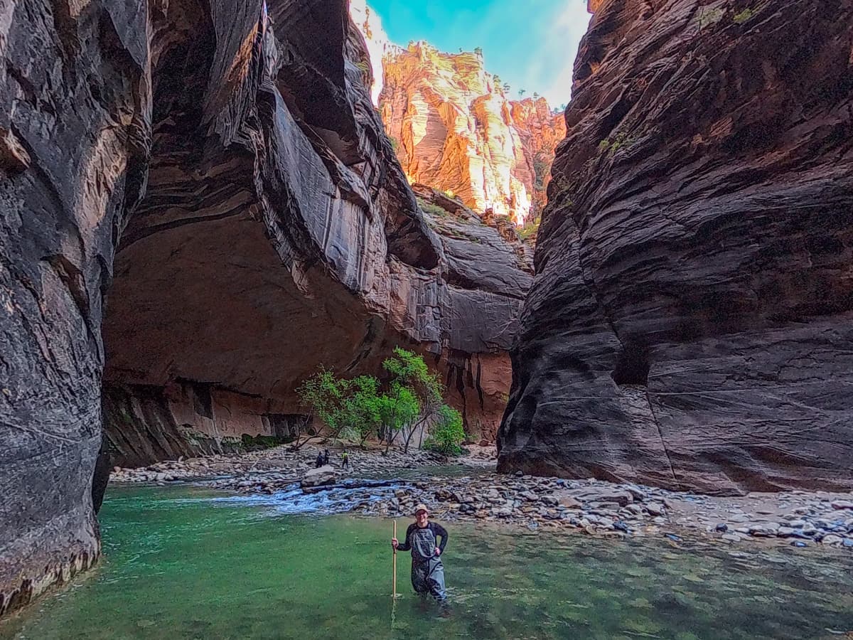 Woman standing in the Virgin River with cliffs in the background along The Narrows trail in Zion National Park
