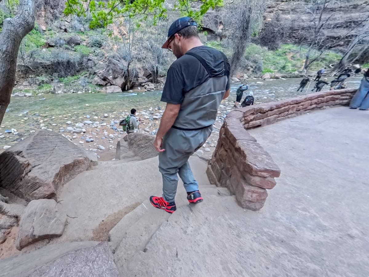 Man wearing waders walking down stairs into the Virgin River to The Narrows trail in Zion National Park