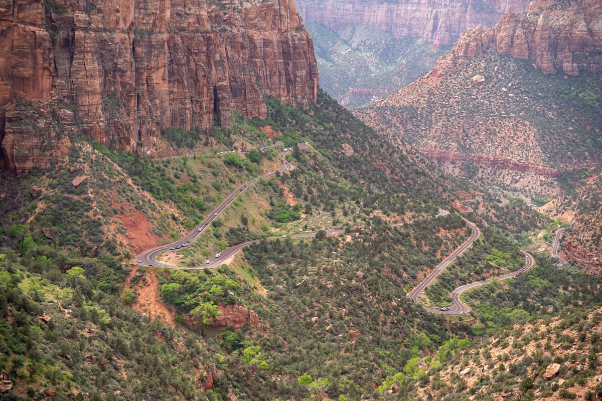 Zion-Mount Carmel Highway snaking down a hillside with mountains in the background in Zion National Park