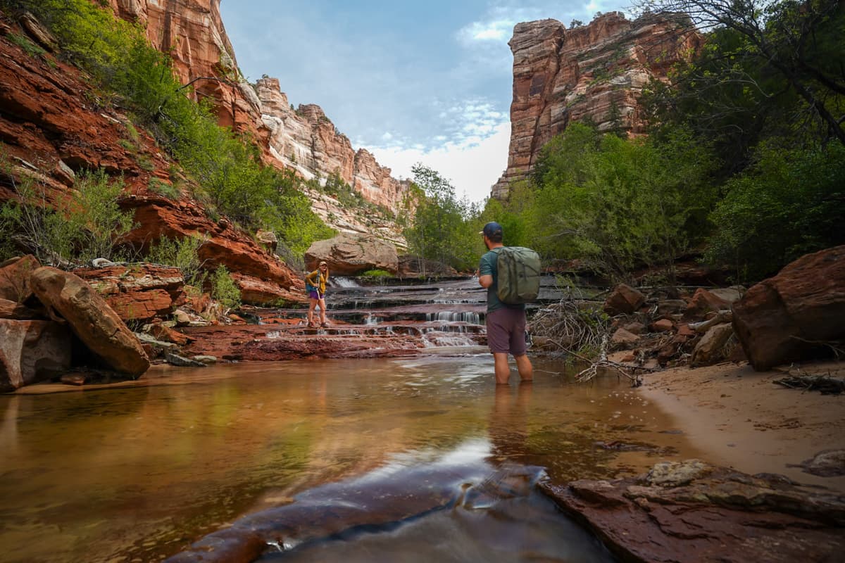 Couple standing in the left fork of North Creek along the Subway Trail in Zion National Park
