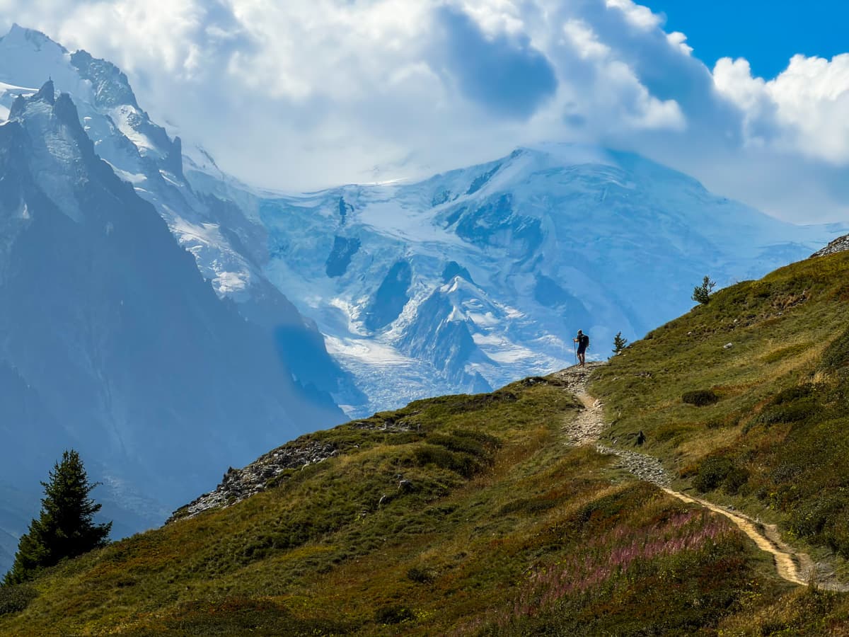 Man standing on a mountain slope with Mont Blanc in the background along the Tour du Mont Blanc near Chamonix, France