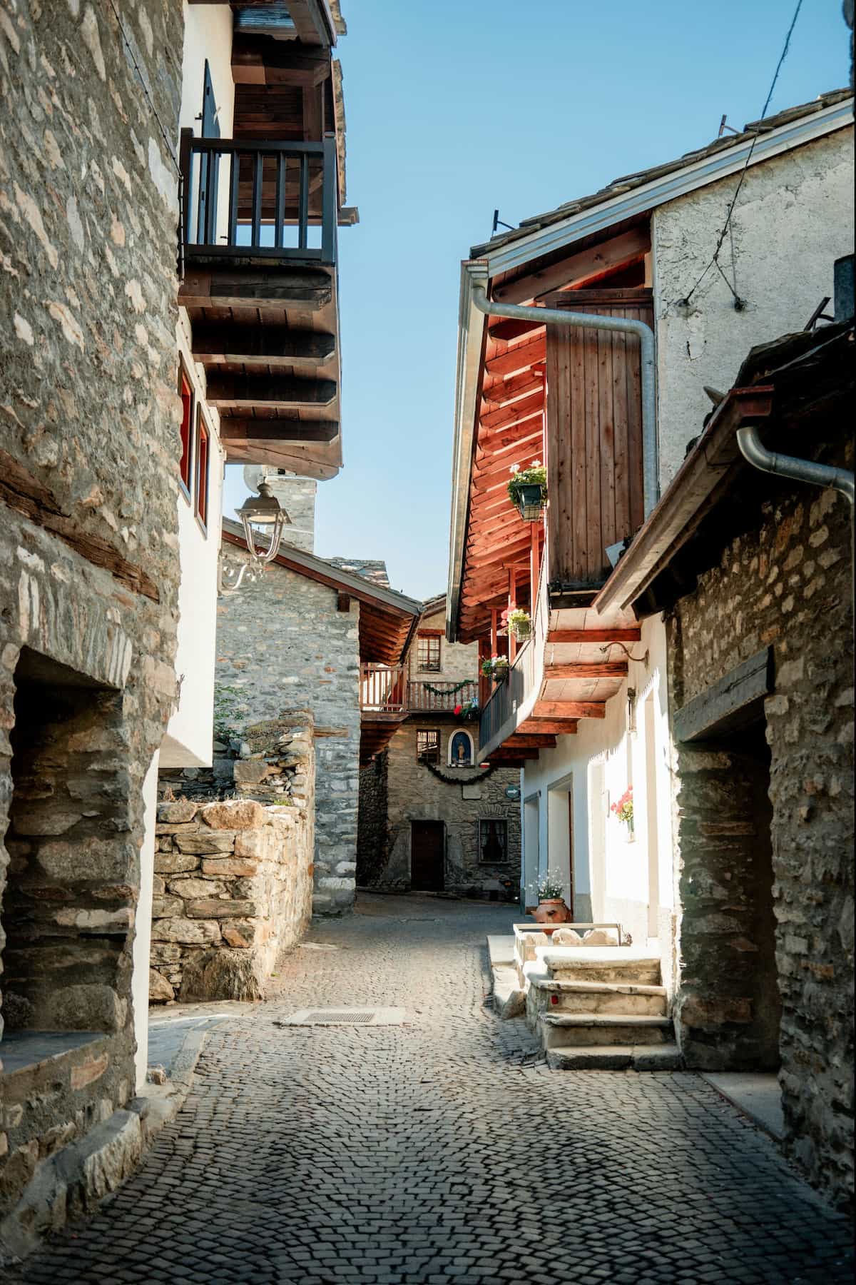 Stone chalets lining a cobblestone alleyway in Courmayeur, Italy along the Tour du Mont Blanc