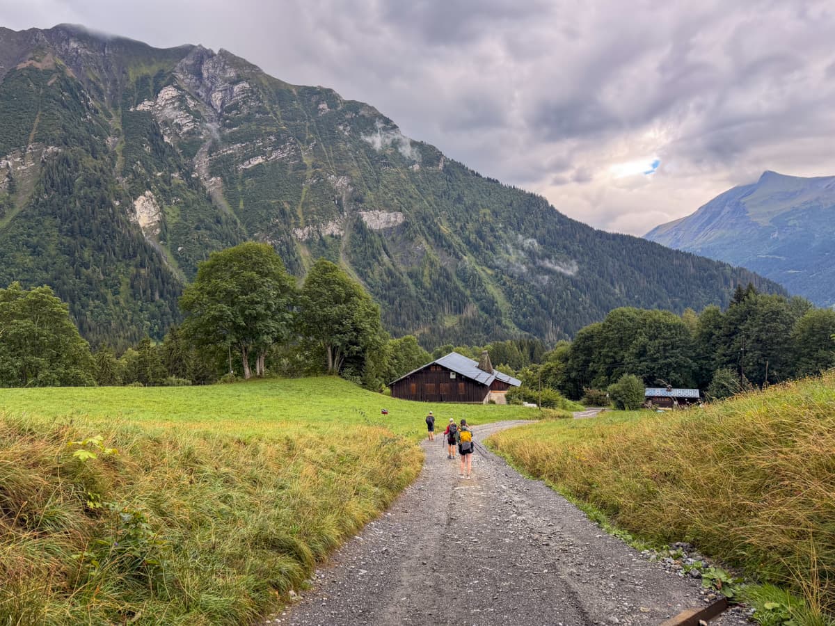 Hikers walking downhill through a small French hamlet along Stage 1 of the Tour du Mont Blanc