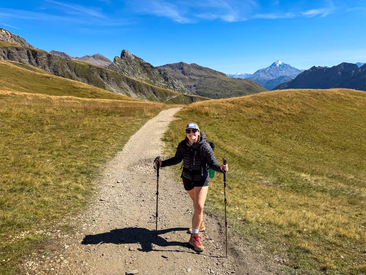 Woman smiling on a dirt pathway with French Alps in the background near Les Chapieux, France along the Tour du Mont Blanc