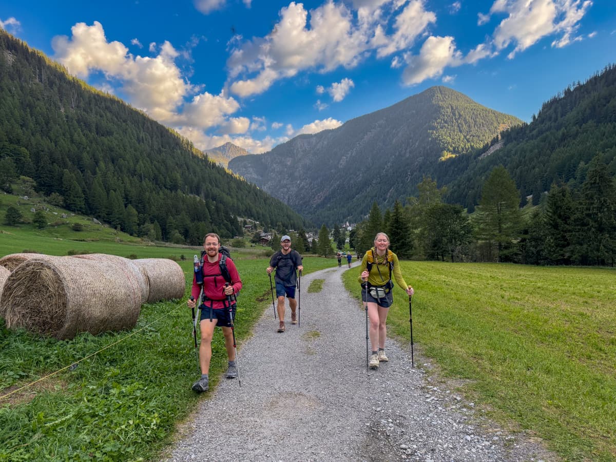 Three friends hiking with Switt Alps in the background outside of Trient, Switzerland along the Tour du Mont Blanc