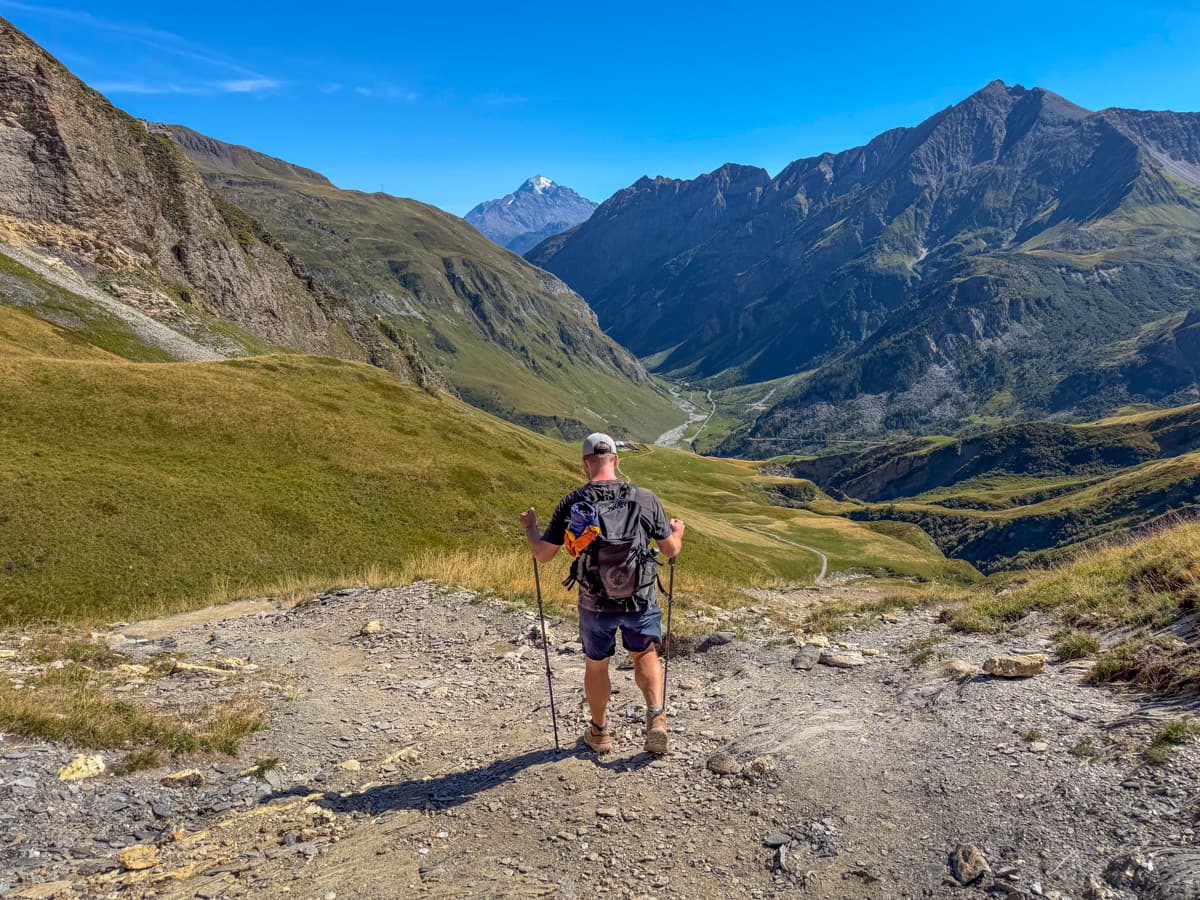 Man hiking down to Les Chapieux, France with the French Alps in the background along the Tour du Mont Blanc