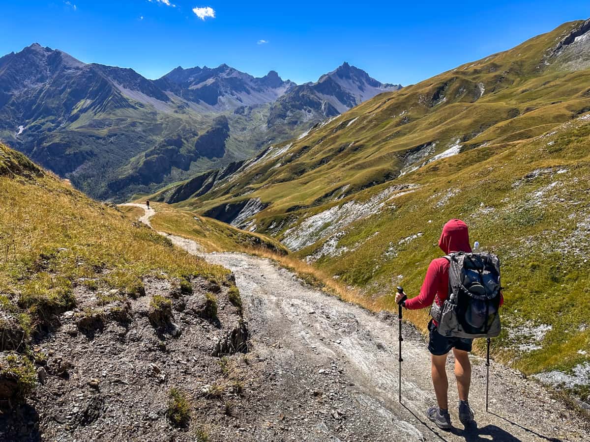 Man hiking along a gravel pathway in the French Alps near Les Chapieux, France along the Tour du Mont Blanc