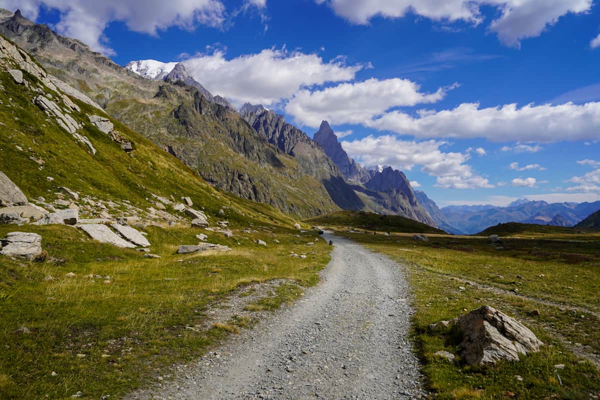 Gravel pathway leading to the jagged peaks of the Italian Alps along the Tour du Mont Blanc