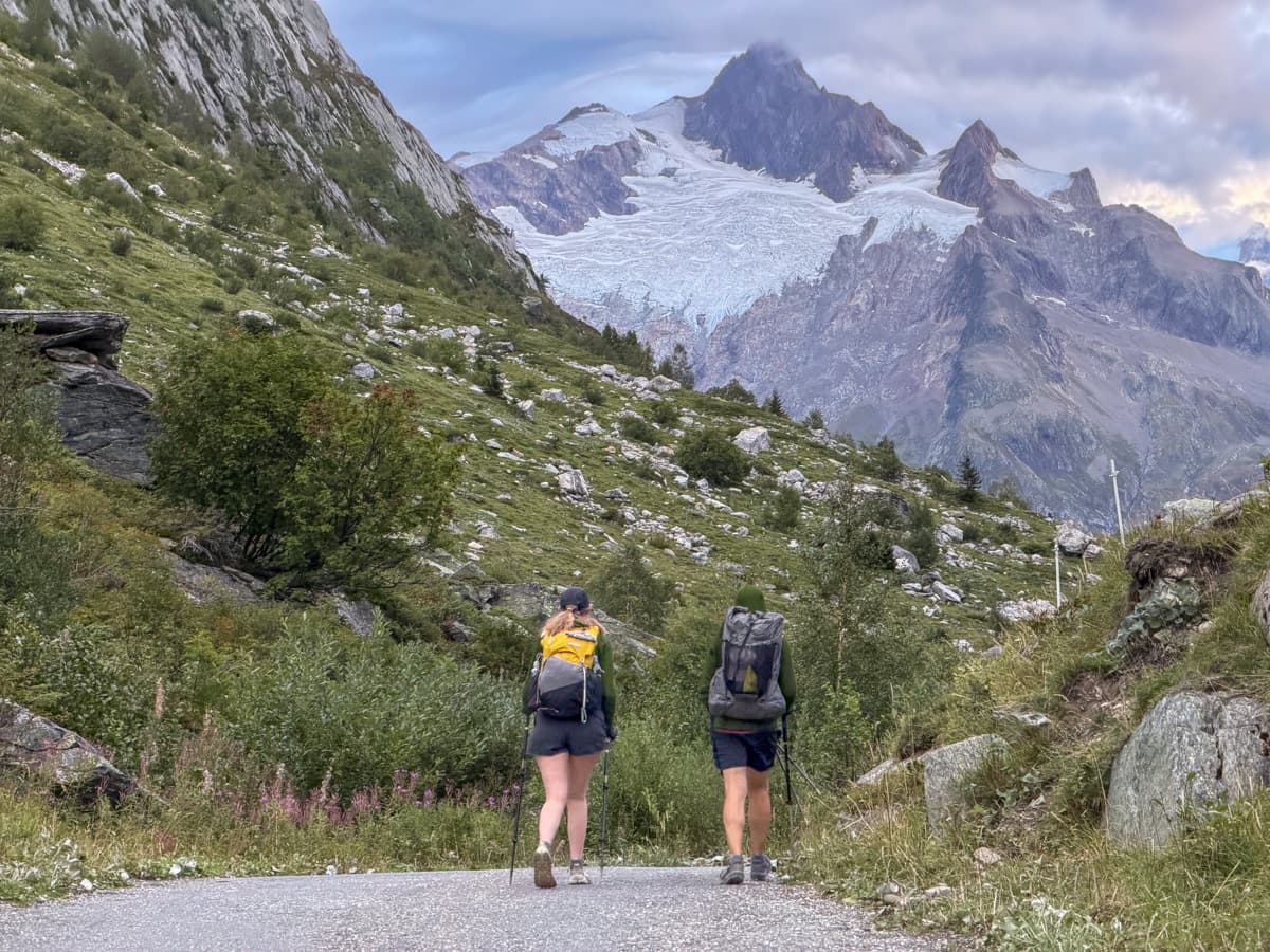 Two hikers walking along a pathway toward the Vallée des Glaciers outside of Les Chapieux, France along the Tour du Mont Blanc