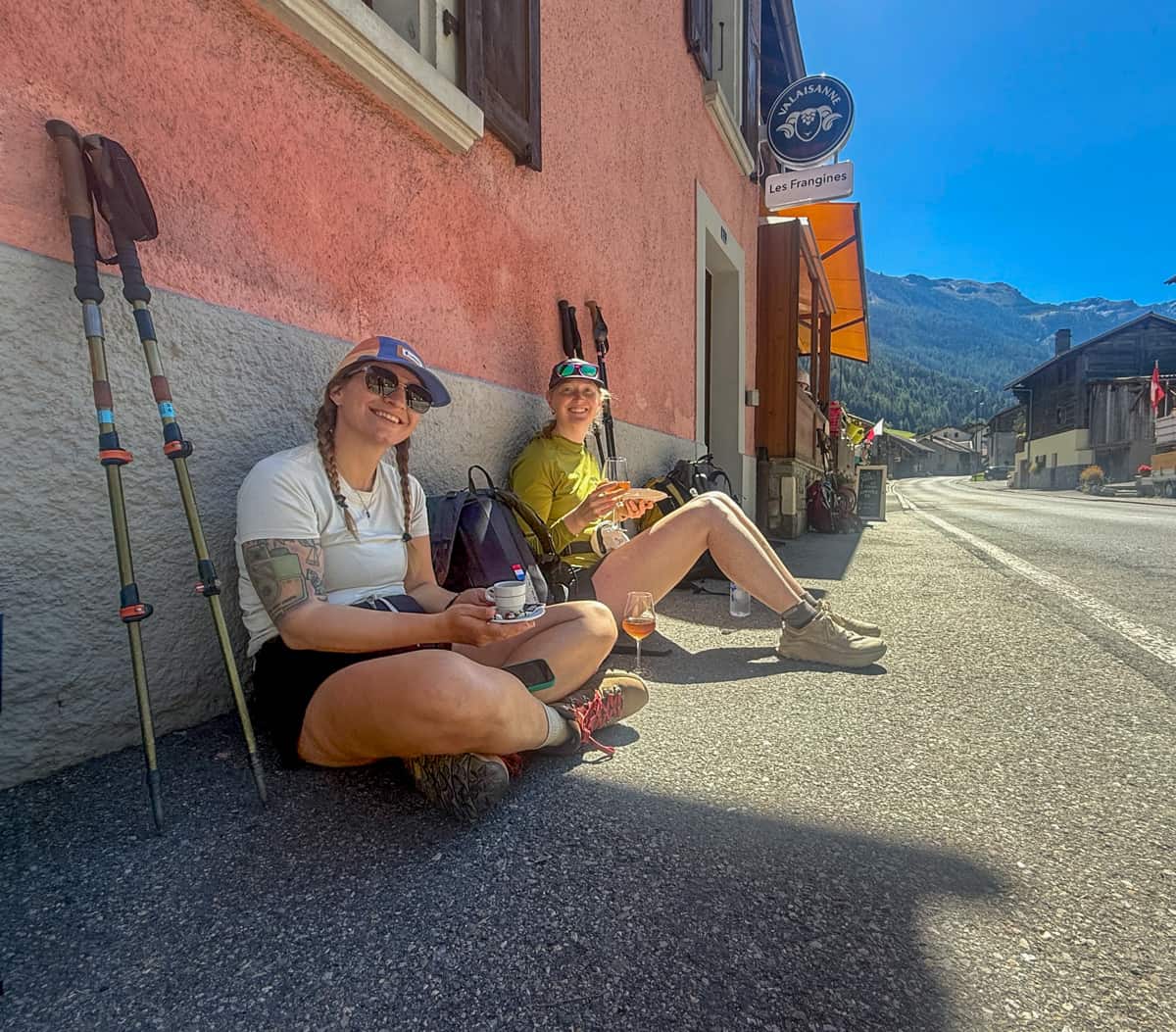 Two friends smiling while having drinks outside of Orsières, Switzerland along the Tour du Mont Blanc