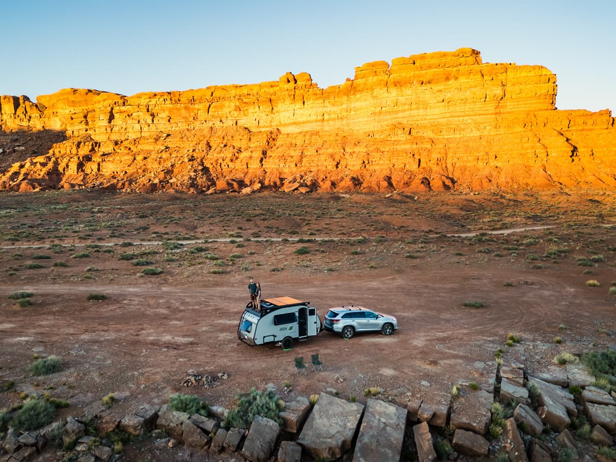 Couple standing on top of their Safari Condo Alto F1743 Expedition while it's hooked up to a Toyota Highlander Hybrid SUV with a rock formation in the background in the Valley of the Gods, UTah