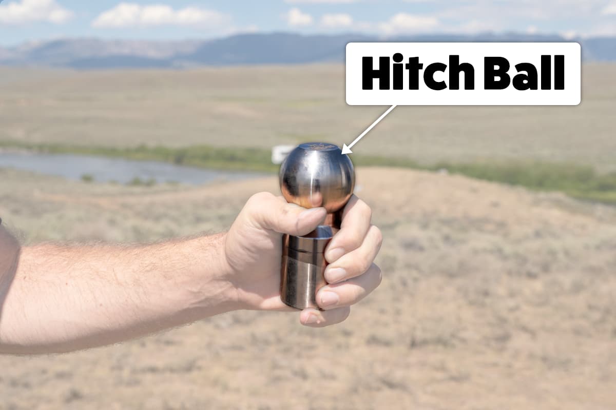 Diagram of a man holding a hitch ball in his hand with mountains in the background