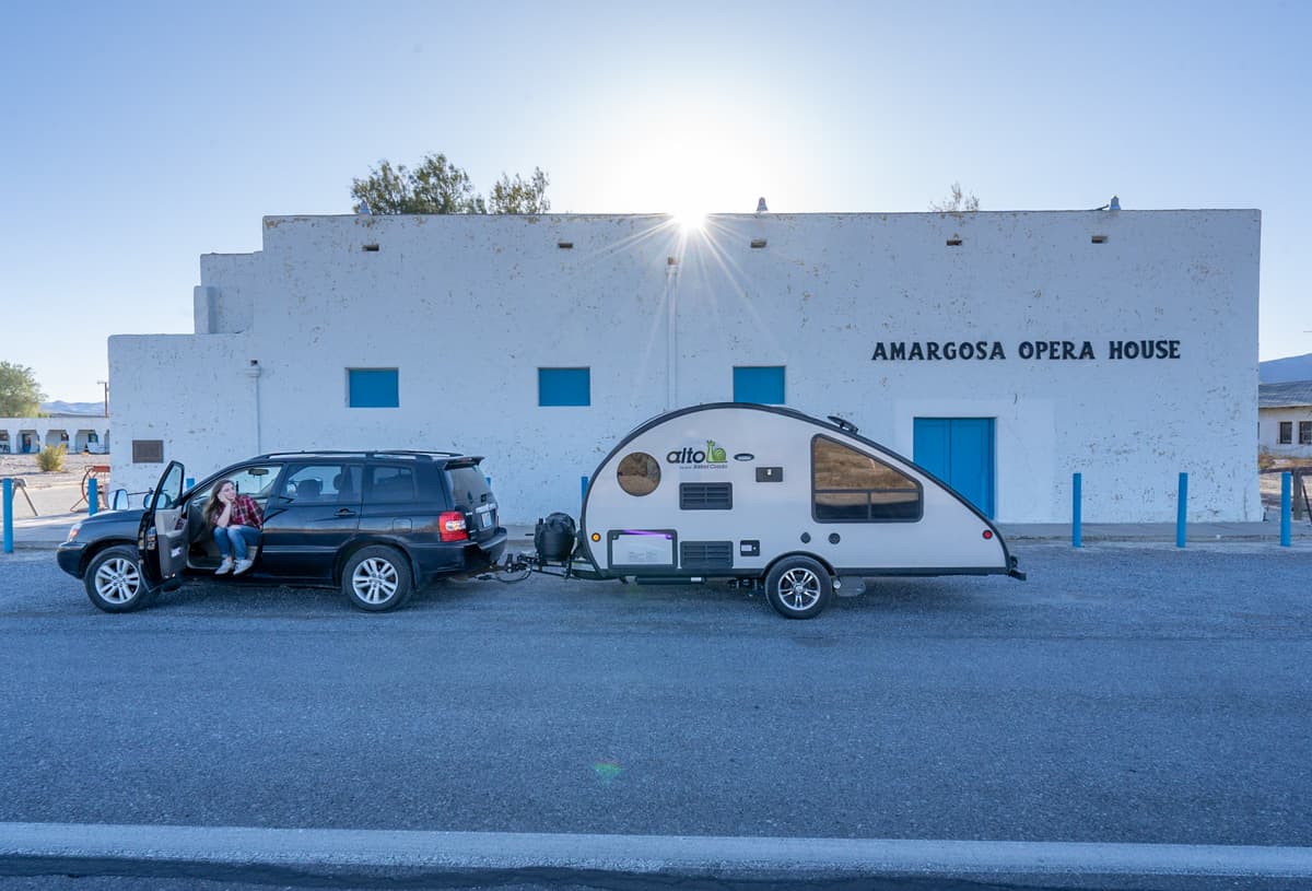 Woman sitting in a Highlander Hybrid SUV towing a Safari Condo Alto R1723 trailer in front of the Amargosa Opera House near Death Valley California