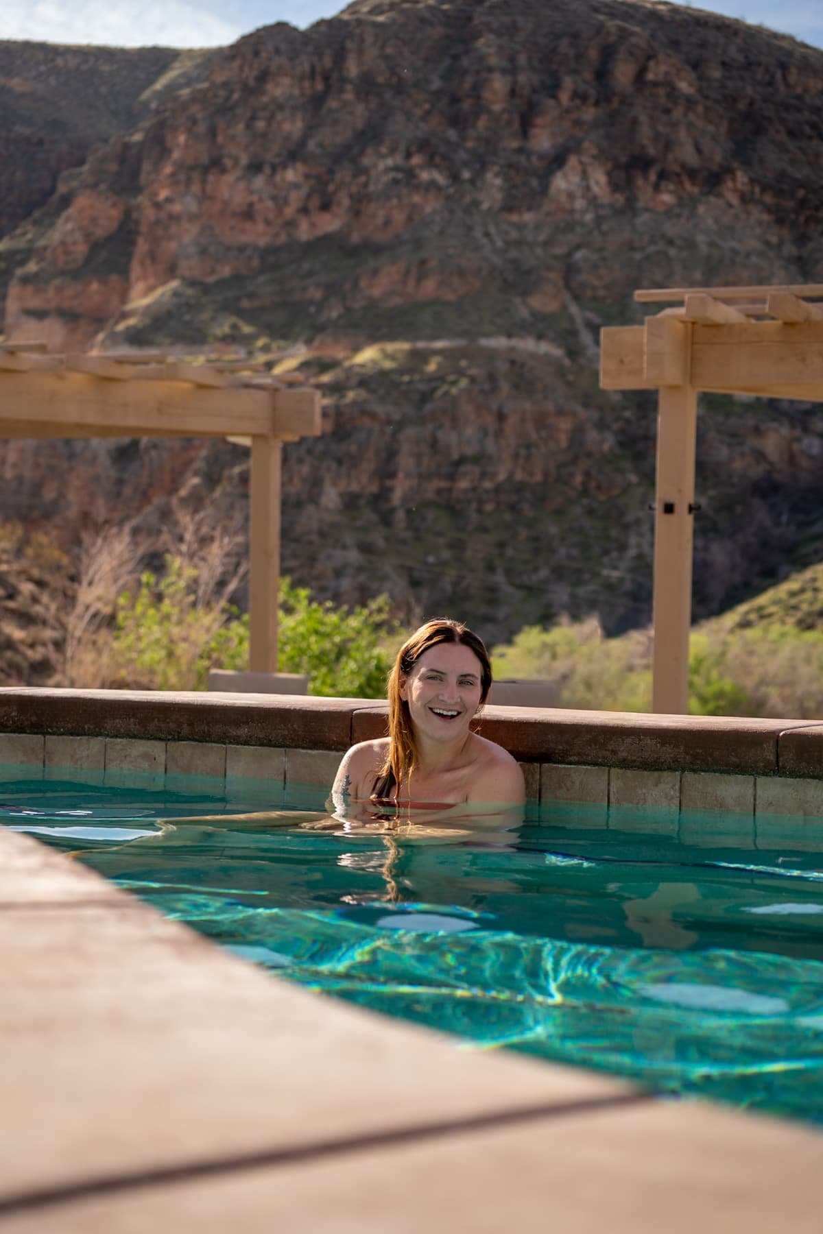 Woman sitting in a pool with a red rock canyon in the background at Zion Canyon Hot Springs with La Verkin, Utah