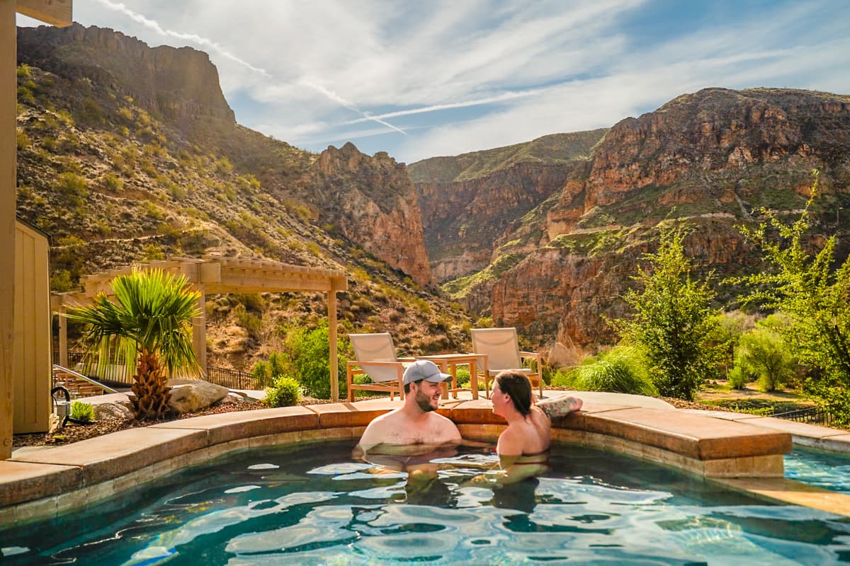 Couple sitting in a pool at Zion Canyon Hot Springs with red rock canyons in the background in La Verkin, Utah