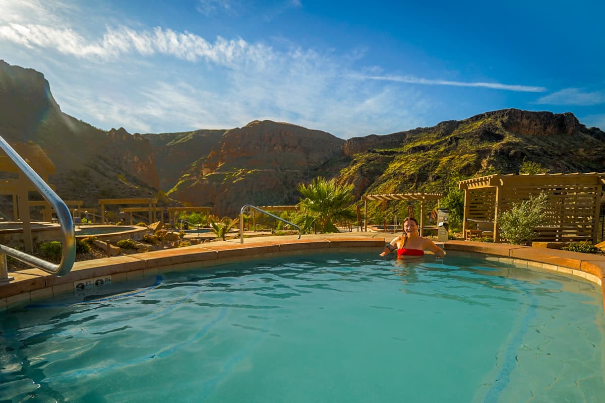Woman soaking in a pool in the Zion Canyon Hot Springs with red rock canyons in the background in La Verkin, Utah