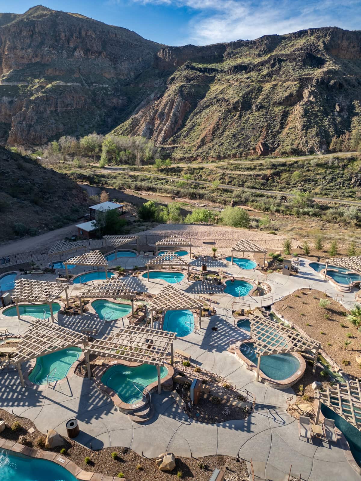 Aerial view of hot spring pools in Zion Canyon Hot Springs with red rock cliffs in the background in La Verkin, Utah