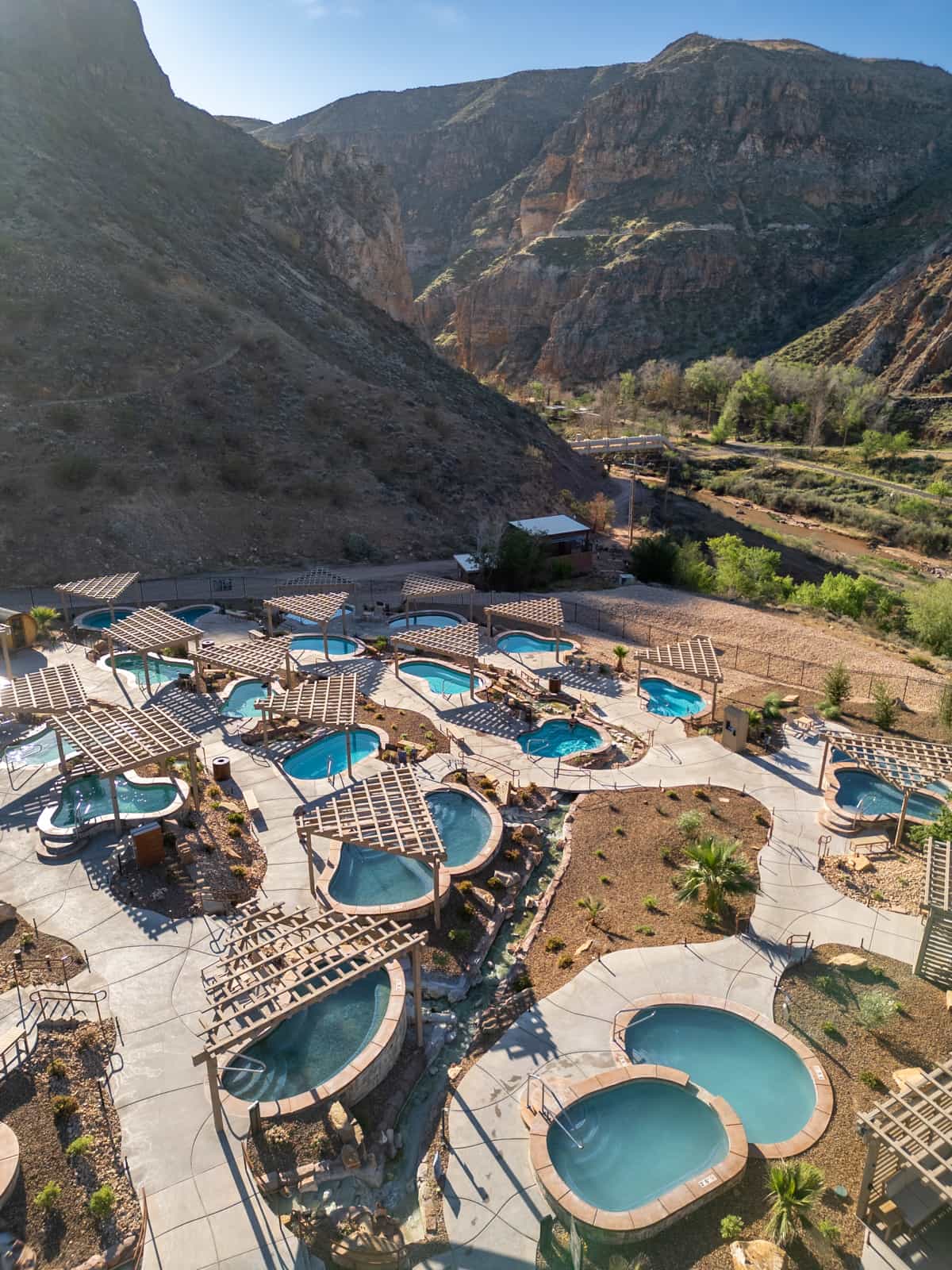 Aerial view of hot springs pools at Zion Canyon Hot Springs with red rock canyon walls in the background in La Verkin, Utah